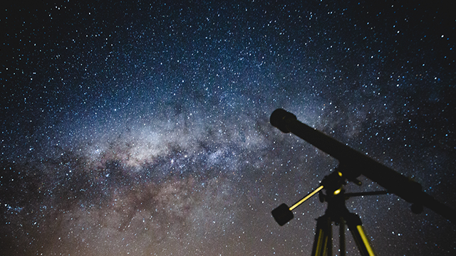 Image of a telescope with a starry night sky behind it