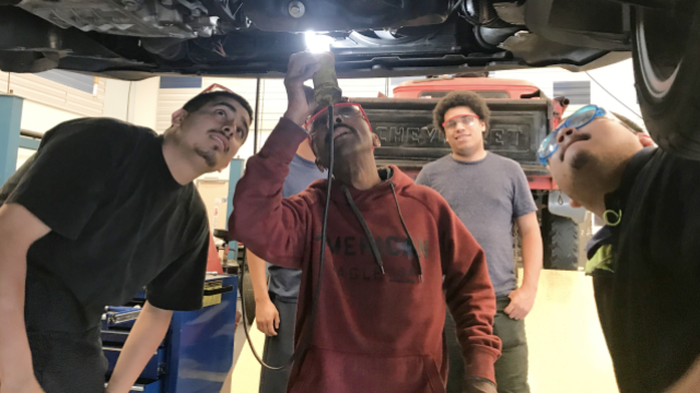 Students working on the undercarriage of a car