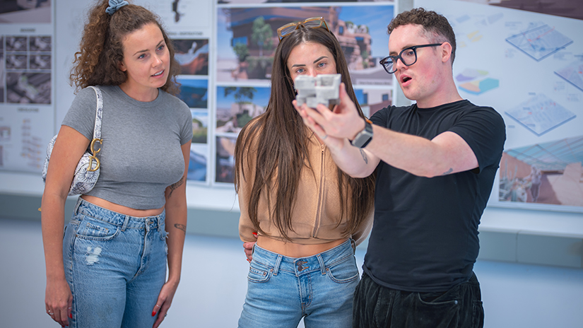 Beau Carter showing his Architecture Studio 1 final model to two guests at the student showcase